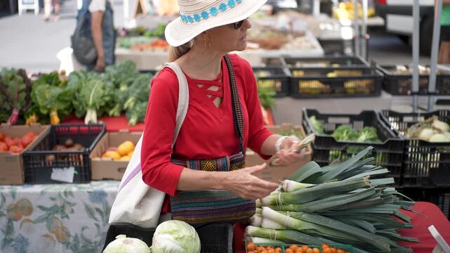 Senior woman smiles as she selects fresh vegetables at the Farmers Market in Sonoma, California, on a bright sunny morning.