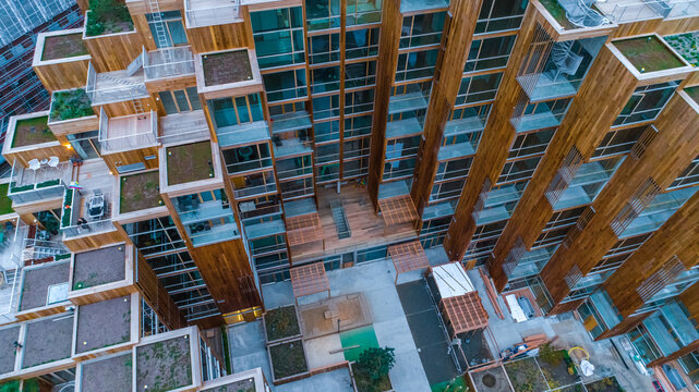 Aerial view of a modern timber apartment building with green roofs, wooden balconies, and glass facades in Sweden.