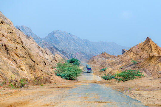 View of the Sulaiman Mountains landscape with a road winding through arid rocky terrain and sparse green bushes in De-excluded Area Dera Ghazi Khan, Punjab, Pakistan.