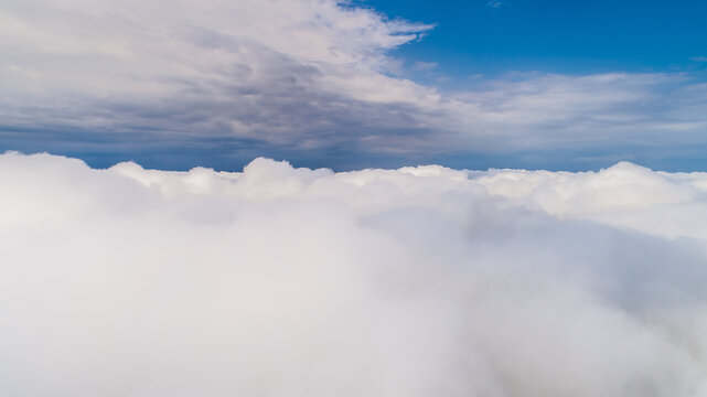 Aerial view of a vast expanse of white clouds under a bright blue sky in Latvia.