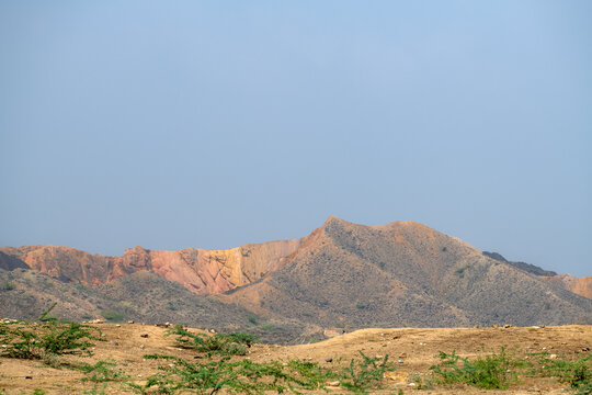 View of the arid landscape of the Sulaiman Mountains with rocky terrain and sparse vegetation under a clear blue sky in De-excluded Area Dera Ghazi Khan, Punjab, Pakistan.