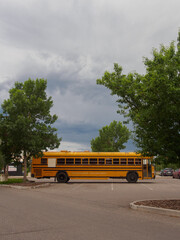Yellow school bus parked under a dramatic cloudy sky © Volodymyr