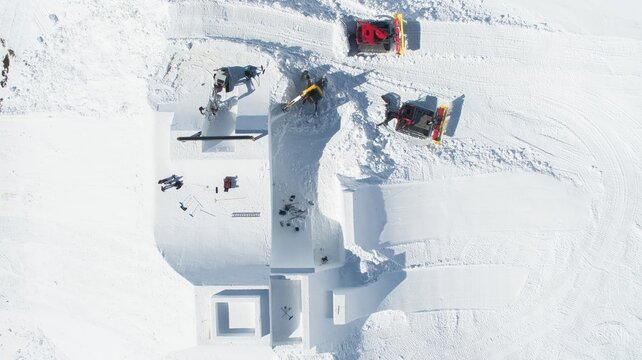 Aerial view of the Watles ski area with snow groomers preparing snow features and workers on the slopes in Mals, Trentino-Alto Adige, Italy.