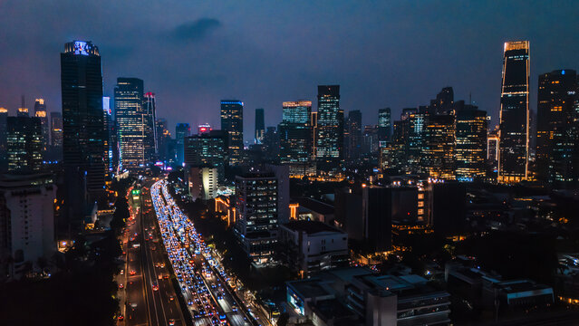 Aerial view of the illuminated Jakarta skyline at night featuring dense traffic on the highway and glowing skyscrapers in Jakarta, Indonesia.