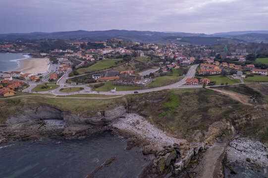 Aerial view of the coastal town of Comillas with its historic architecture, sandy beach, and rugged cliffs along the Cantabrian Sea in Comillas, Cantabria, Spain.