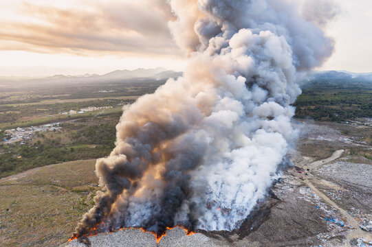 Aerial view of the Duquesa Landfill on fire with a massive plume of smoke rising into the sky over the landscape in Pantoja, Santo Domingo, Dominican Republic.