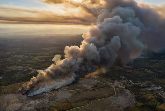 Aerial view of the Vertedero Duquesa landfill fire with a massive plume of smoke rising into the sky during golden hour in Pantoja, Santo Domingo, Dominican Republic.