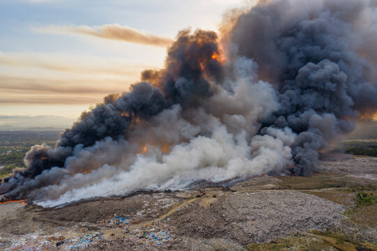 Aerial view of a massive fire at the Vertedero duquesa landfill with thick plumes of black and white smoke rising into the sky at sunset in Pantoja, Santo Domingo, Dominican Republic.