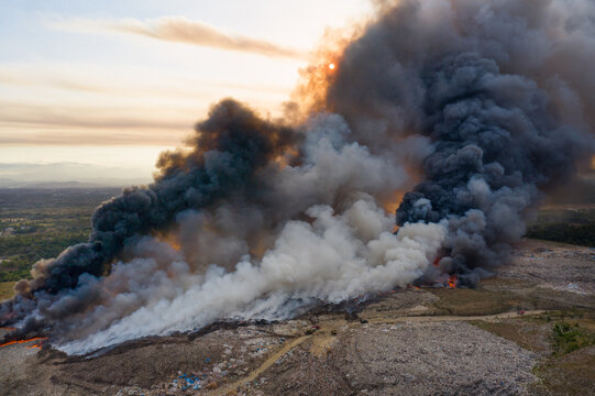 Aerial view of the massive fire at the Duquesa Landfill with thick plumes of black and white smoke rising into the sky at sunset in Pantoja, Santo Domingo, Dominican Republic.