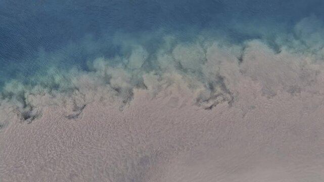 Aerial view of the confluence of glacial river waters with distinct silt-laden sediment mixing into clear blue currents in Selfoss, Sveitarfelagid Arborg, Iceland.