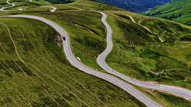 Aerial view of the winding Col d'Aubisque mountain road surrounded by lush green hills and grassy slopes in Beost, Nouvelle-Aquitaine, France.