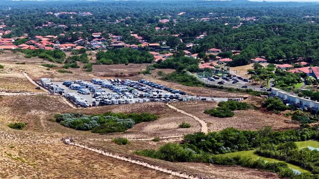 Aerial view of Plage des Oceanides parking area filled with camper vans near the pine forest and coastline in Capbreton, Nouvelle-Aquitaine, France.