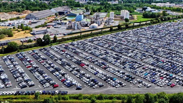 Aerial view of the Port of Bordeaux vehicle storage area with rows of parked cars and industrial facilities in Bassens, Nouvelle-Aquitaine, France.