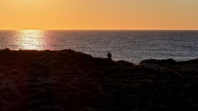 Aerial view of Plage des Oceanides at sunset with a person standing on the cliff overlooking the sea in Capbreton, Nouvelle-Aquitaine, France.