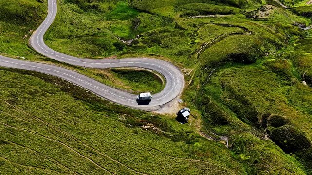 Aerial view of the winding mountain road at Col d'Aubisque with a camper van parked on the grassy slopes in Beost, Nouvelle-Aquitaine, France.