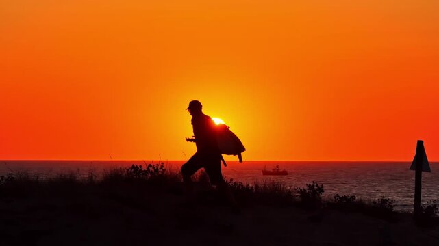 Aerial view of a person walking in silhouette along the dunes at Plage des Oceanides during a vibrant sunset over the Atlantic Ocean in Capbreton, Nouvelle-Aquitaine, France.