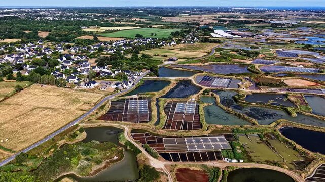 Aerial view of salt pans and marshes with a small town and green fields in the background in Capbreton, Nouvelle-Aquitaine, France.