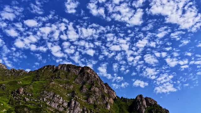 Aerial view of the rugged mountain peaks of Col d'Aubisque under a bright blue sky with scattered clouds in Beost, Nouvelle-Aquitaine, France.