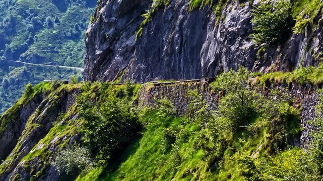 Aerial view of the rugged mountain pass at Col d'Aubisque with steep rocky cliffs, lush green slopes, and winding roads in Beost, Nouvelle-Aquitaine, France.