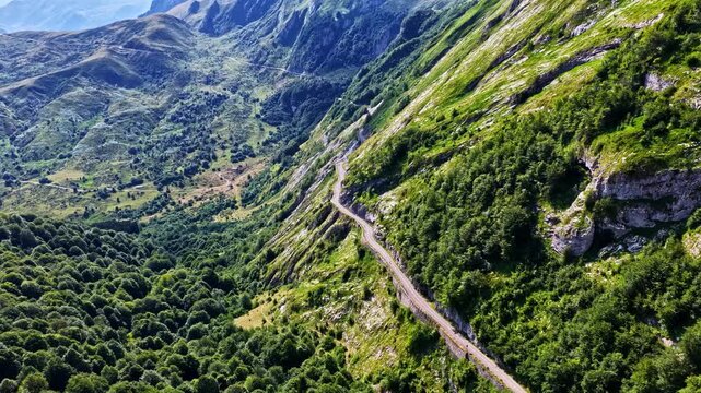 Aerial view of the winding road at Col d'Aubisque, surrounded by lush green mountain slopes, dense forests, and rocky terrain in Beost, Nouvelle-Aquitaine, France.