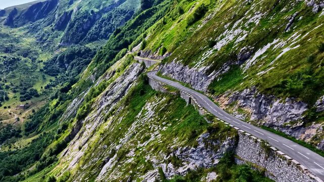 Aerial view of the winding Col d'Aubisque mountain pass road carved into the steep, rocky, and lush green slopes of the Pyrenees in Beost, Nouvelle-Aquitaine, France.