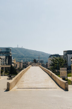 View of the historic Stone Bridge leading towards the city center with modern buildings and a mountain in the background in Skopje, Greater Skopje, North Macedonia.