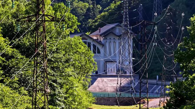 Aerial view of a building nestled among dense forest trees near high-voltage power lines in the Pyrenees mountains in Beost, Nouvelle-Aquitaine, France.