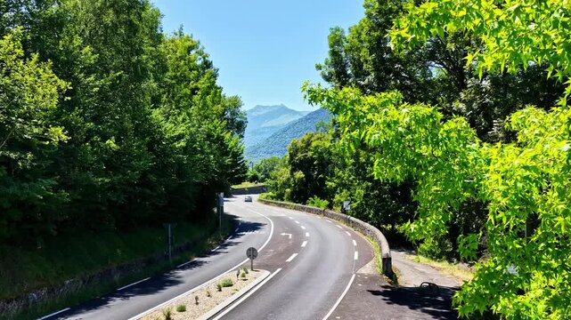 Aerial view of the winding road leading to Col d'Aubisque surrounded by lush green trees and mountain scenery in Beost, Nouvelle-Aquitaine, France.