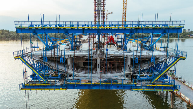 Aerial view of the bridge construction site over the Danube River with steel scaffolding and heavy machinery in Novi Sad, Serbia.