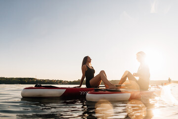 Fototapeta premium Women relaxing on paddleboards at sunset