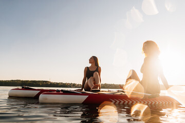 Fototapeta premium Women relaxing on stand up paddleboards at sunset