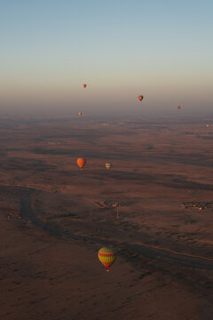 View of colorful hot air balloons drifting over the vast desert landscape at sunrise, Marrakesh, Marrakesh-Safi, Morocco.