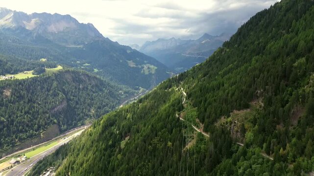 Aerial view of mountain valley with lush forests and winding road in Quinto di Treviso, Veneto, Italy.