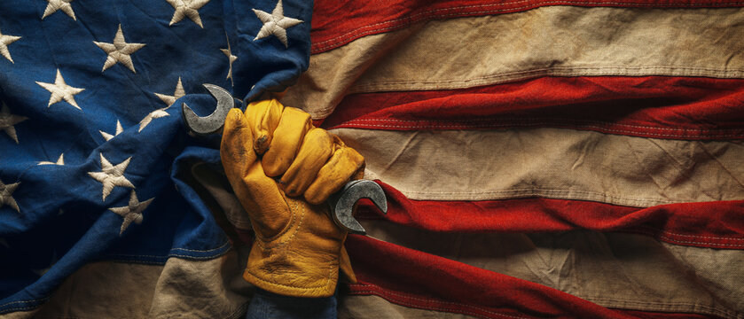 Worn work glove holding wrench on the American flag. Symbolic of hardworking blue collar workers, USA manufacturing, pride in products Made in United States of America, or to celebrate US Labor Day.