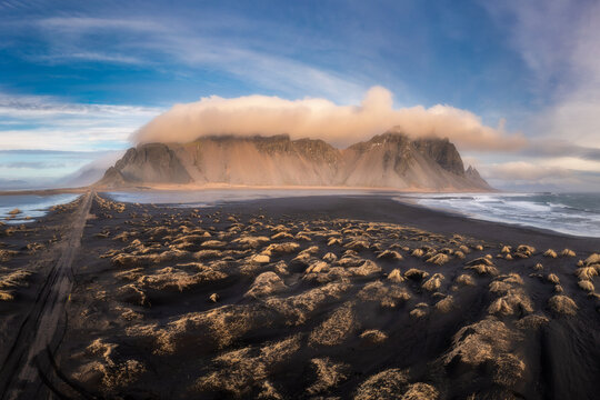 Aerial view of Vestrahorn mountain rising above the black sand dunes and rugged coastline of Iceland.