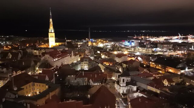 Aerial view of illuminated historic rooftops and St. Olaf's Church in the old town of Tallinn at night, Tallinn, Harju County, Estonia.