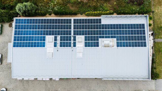 Aerial view of a large industrial building roof covered with extensive solar panel arrays, featuring skylights and metal roofing in Novi Sad, Vojvodina, Serbia.