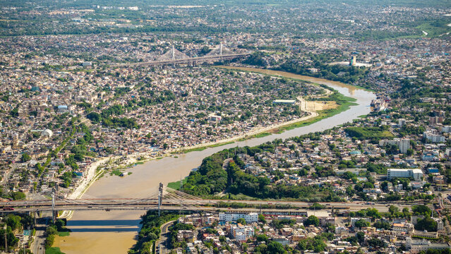 Aerial view of Rio Ozama winding through the dense urban landscape, featuring cable-stayed bridges and residential neighborhoods in Santo Domingo, DN, Dominican Republic.