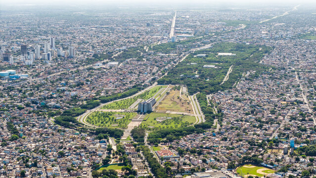 Aerial view of the Faro a Colon monument surrounded by lush green parks and dense urban residential neighborhoods in Santo Domingo, DN, Dominican Republic.