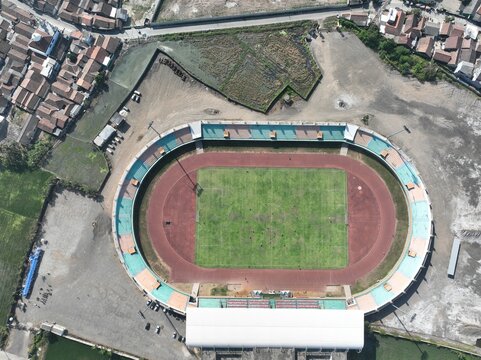 Aerial view of Krakatau Steel Stadium featuring a green football pitch surrounded by a red running track and stadium seating in Cilegon, Banten, Indonesia.