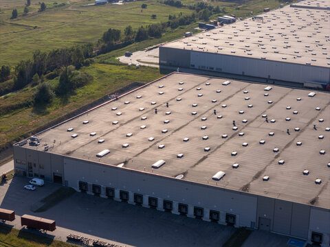 Aerial view of a large logistics warehouse facility with multiple loading docks and a flat roof with skylights in Gdansk, Pomeranian Voivodeship, Poland.