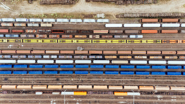 Aerial view of a busy railway yard filled with colorful freight train cars and cargo containers arranged on parallel tracks in Novi Sad, Vojvodina, Serbia.