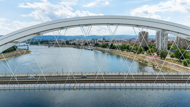 Aerial view of the Zezelj Bridge spanning the Danube river with cars crossing and the city skyline in the background in Novi Sad, Vojvodina, Serbia.