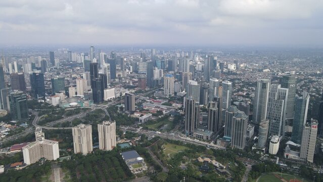 Aerial view of Gelora Bung Karno Stadium surrounded by the dense modern skyline and high-rise buildings of Jakarta in Kecamatan Tanah Abang, Daerah Khusus Ibukota, Indonesia.