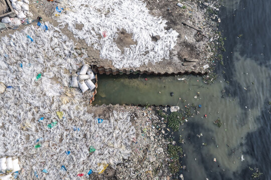 Dhaka, Bangladesh - 23 January 2026: Aerial view of Buriganga River showing extensive plastic waste accumulation along the riverbank with discarded bags and polluted water.