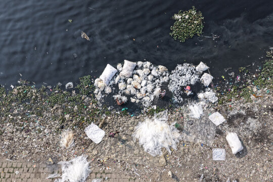 Dhaka, Bangladesh - 23 January 2026: Aerial view of workers sorting through plastic waste and debris in the polluted waters of the Buriganga River.