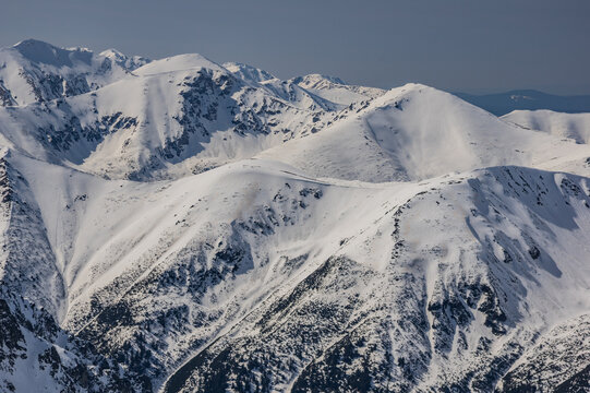 Aerial view of Liptovske kopy mountains covered in deep snow under a clear sky as seen from Koprovsky Stit in Vysoke Tatry, Presov Region, Slovakia.