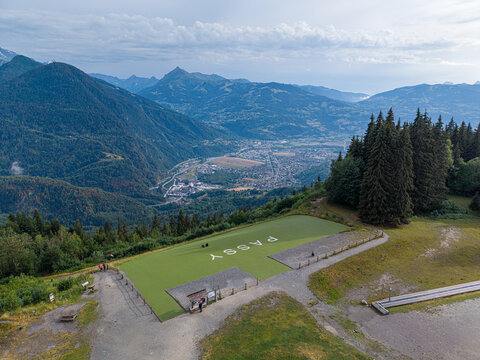 Aerial view of Plaine Joux with its green landing area and the town of Passy nestled in the valley, surrounded by mountains, Passy, Auvergne-Rhone-Alpes, France.