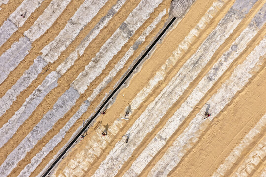 Brahmanbaria, Bangladesh - 24 January 2026: Aerial view of workers spreading and drying harvested grain on large white sheets in Ashuganj, showcasing traditional agricultural practices.
