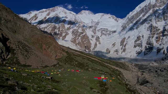 Aerial view of colorful tents at the Nanga Parbat base camp on the Diamir face, surrounded by snow-capped peaks and glaciers in Diamir, Gilgit Baltistan, Pakistan.